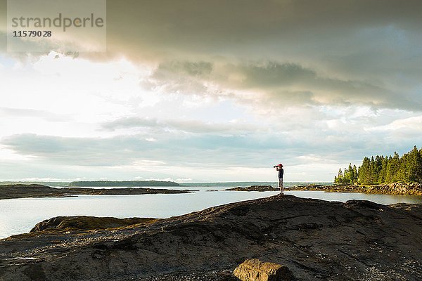 Ferngesehener Blick eines älteren Mannes durch ein Fernglas an der Küste von Maine  USA