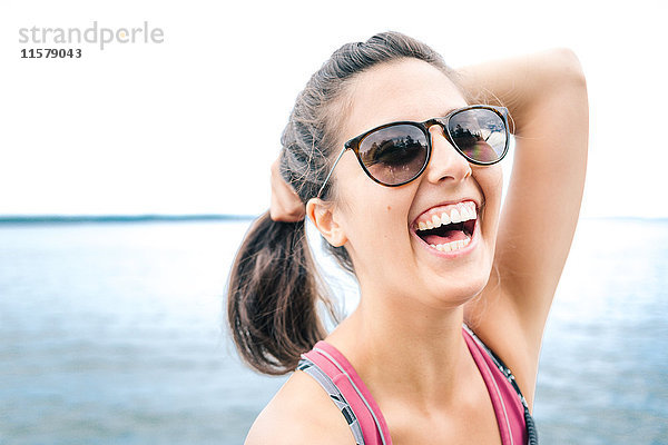 Junge Frau mit Sonnenbrille lacht auf See  Maine  USA