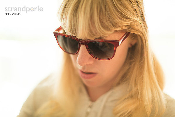 Blonde Frau mit Sonnenbrille mit Blick nach unten