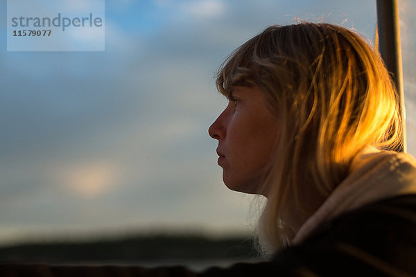 Frau schaut bei Sonnenuntergang an der Küste von Maine  USA  aus dem Boot