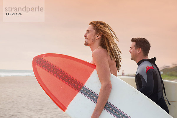 Männlicher Rettungsschwimmer und Surfer  der vom Strand auf das Meer schaut