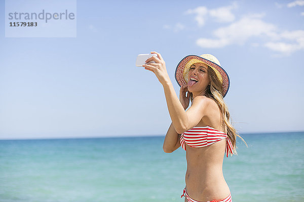 Hübsche Frau beim Selfie am Strand