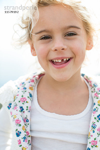 Porträt eines süßen blonden Mädchens mit fehlendem Zahn an der Küste