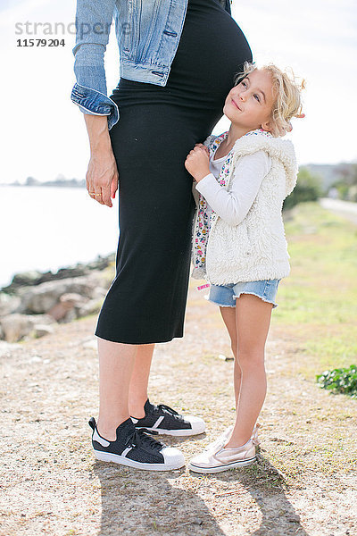 Schnappschuss von schwangerer Mutter und Tochter an der Küste