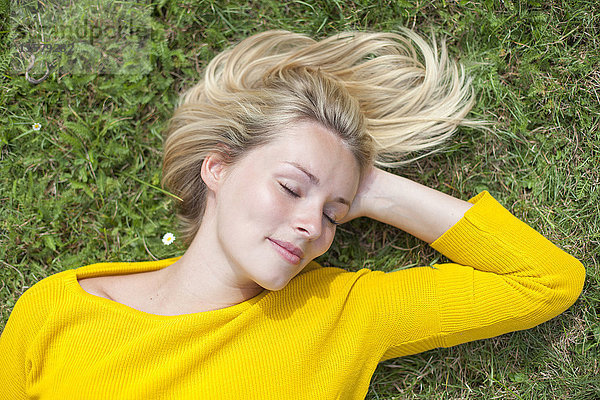 Porträt einer hübschen blonden Frau im Park mit geschlossenen Augen