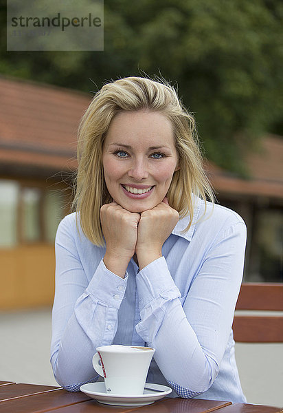 Hübsche blonde Frau in einem Cafe lächelnd vor der Kamera