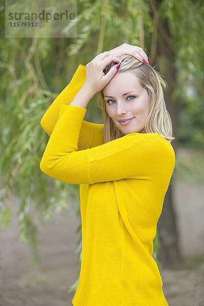 Porträt einer sinnlichen Blondine im Park mit Blick auf die Kamera