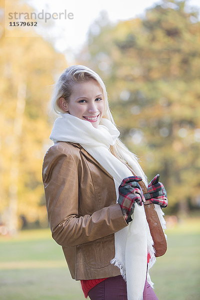 Portrait einer zufriedenen hübschen blonden Frau mit Handschuhen und Schal im Herbst lächelnd vor der Kamera