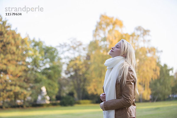 Seitenansicht einer hübschen blonden Frau im Park im Herbst mit geschlossenen Augen