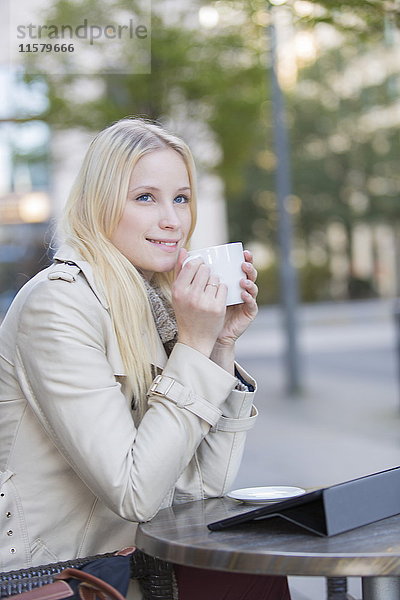 Hübsche blonde Frau genießt eine Tasse Kaffee in der Innenstadt.