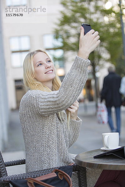 Hübsche junge Frau bei einem Selfie in einem Cafe im Stadtzentrum.