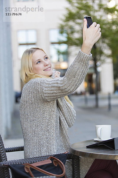 Hübsche junge Frau bei einem Selfie in einem Cafe im Stadtzentrum.