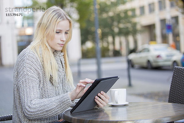 Hübsche junge Frau mit Tablette in einem Cafe im Stadtzentrum