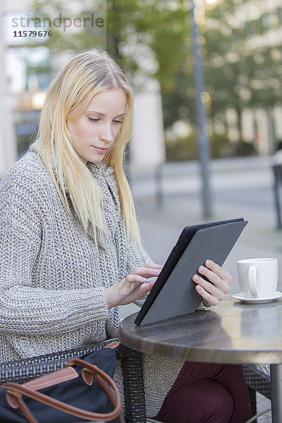 Hübsche junge Frau mit Tablette in einem Cafe im Stadtzentrum