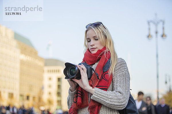 Hübsche blonde Frau mit Digitalkamera beim Fotografieren in einer Stadt in Europa