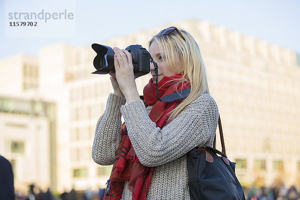 Hübsche blonde Frau mit Digitalkamera beim Fotografieren in einer Stadt in Europa