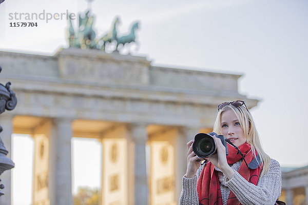 Hübsche blonde Frau fotografiert vor dem Brandenburger Tor in Berlin