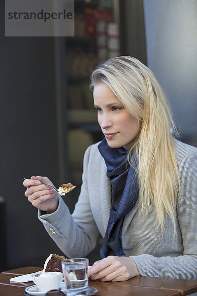Hübsche blonde Frau genießt Kuchen und Kaffee im Stadtzentrum