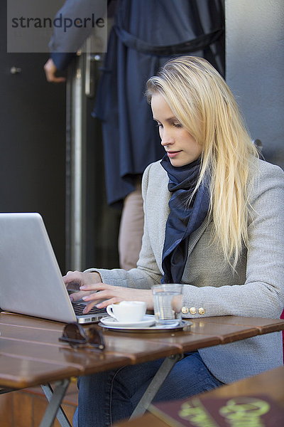 Hübsche blonde Frau mit Laptop in einem Cafe