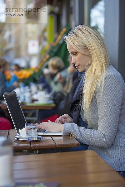 Hübsche blonde Frau mit Laptop in einem Cafe