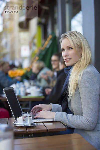 Hübsche nachdenkliche Frau mit Laptop in einem Cafe