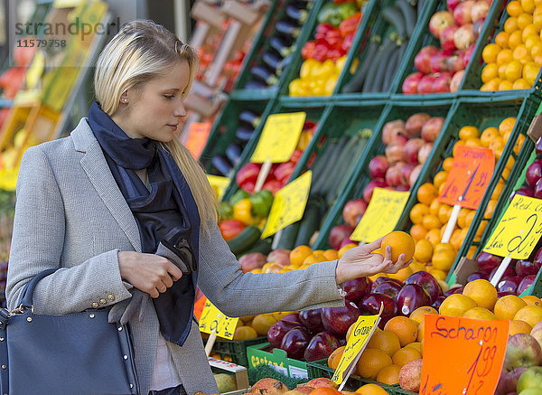 Hübsche blonde Frau  die auf dem Markt gesundes Essen kauft.