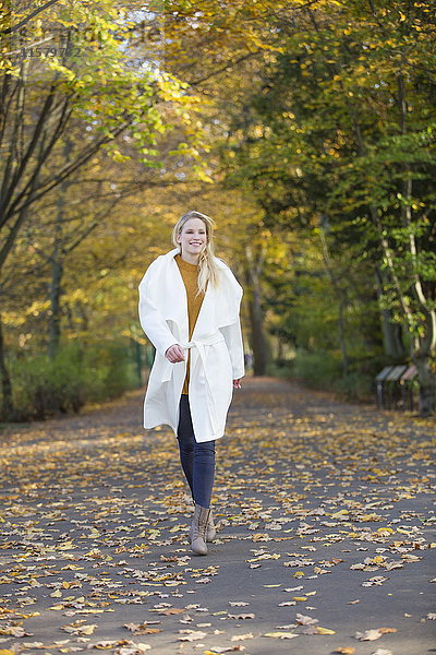Hübsche blonde Frau  die im Herbst im Park spazieren geht.