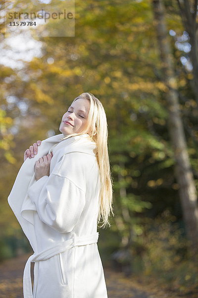 Hübsche blonde Frau mit Mantel im Park im Herbst