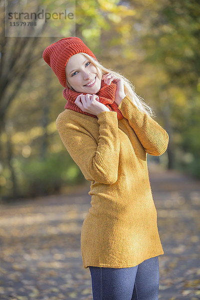 Porträt einer hübschen blonden Frau im Park im Herbst lächelnd vor der Kamera