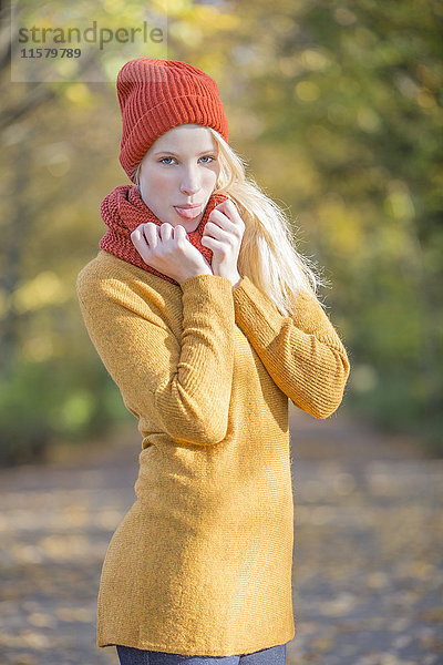 Porträt einer verspielten blonden Frau im Park im Herbst