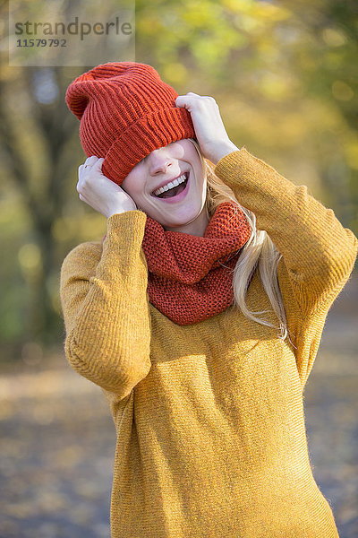 Verspielte junge Frau mit Mütze im Herbst im Park