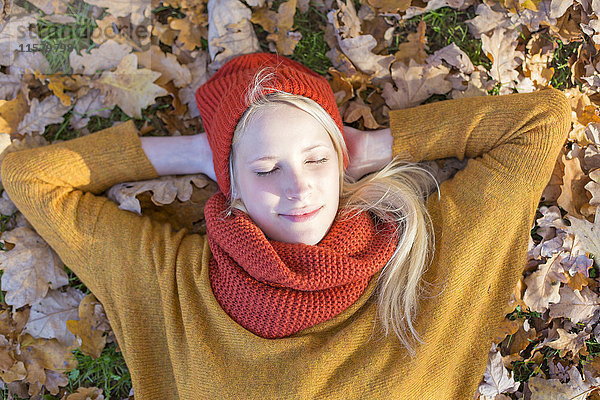 Hübsche blonde Frau im Herbst im Park mit geschlossenen Augen.