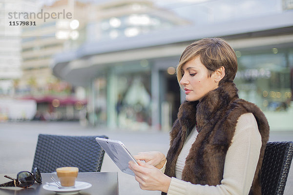Frau mit Tablette in einem Cafe im Freien