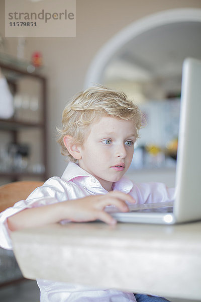 Kleiner Junge mit Laptop zu Hause