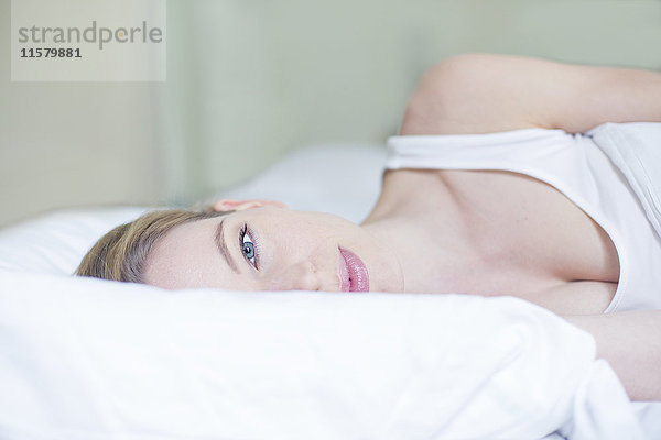 Porträt einer hübschen blonden Frau im Bett mit Blick auf die Kamera