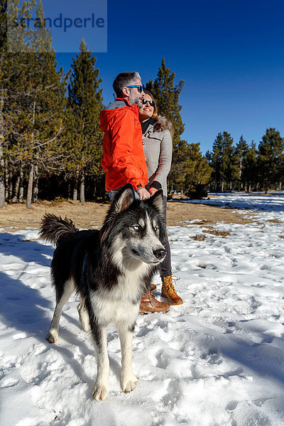 Erwachsenes Ehepaar mit Hund im verschneiten Wald