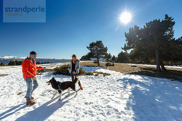 Paar mit Hund in schneebedeckter Landschaft