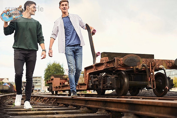 Zwei junge Männer gehen mit Skateboards entlang einer Zugstrecke  Bristol  UK