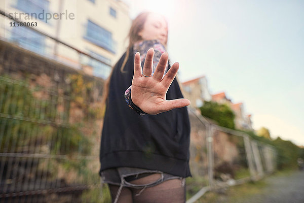 Junge Frau geht im Freien  hält Hand an die Kamera  Rückansicht  Bristol  UK