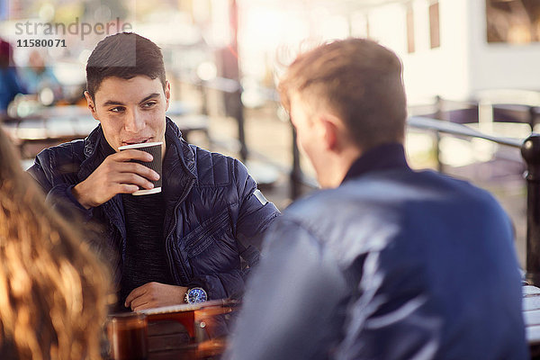 Drei Freunde sitzen im Freien und trinken Kaffee  Bristol  UK