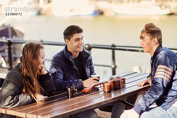 Drei Freunde sitzen im Freien und trinken heiße Getränke  Bristol  UK