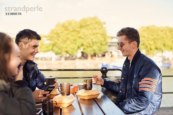 Drei Freunde  sitzen im Freien und trinken heiße Getränke  Bristol  UK