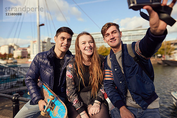 Drei Freunde sitzen draussen und fotografieren sich selbst mit der Kamera  Bristol  UK