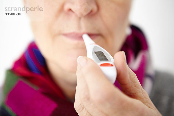 Ältere Frau hält Digitalthermometer im Mund  Nahaufnahme