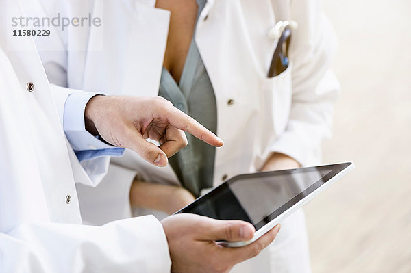 Zwei Ärzte betrachten ein digitales Tablett  mittlerer Abschnitt  Nahaufnahme