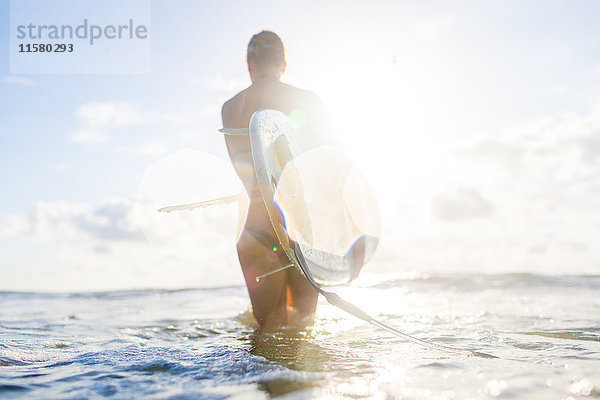 Rückansicht einer Frau mit Surfbrett im sonnenbeschienenen Meer  Nosara  Provinz Guanacaste  Costa Rica