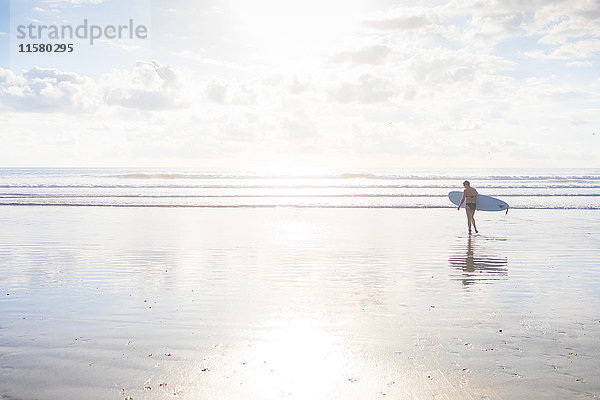 Fernblick einer Frau  die ein Surfbrett am Strand trägt  Nosara  Provinz Guanacaste  Costa Rica