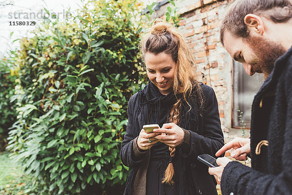 Ehepaar im Garten beim Betrachten von Smartphones