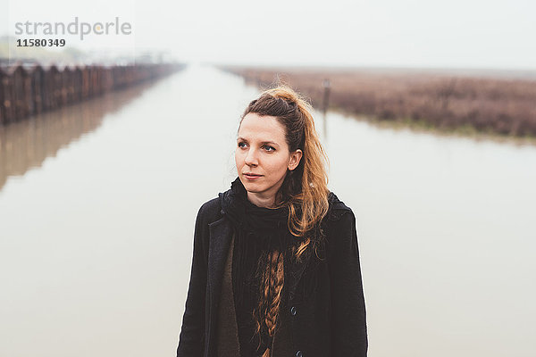 Porträt einer jungen Frau am Ufer des nebligen Kanals