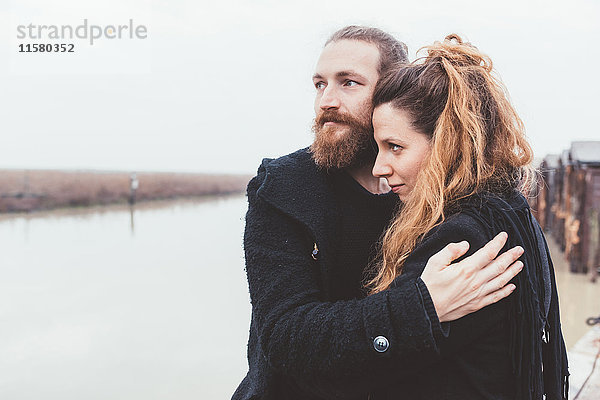 Ehepaar umarmt sich am Ufer des nebligen Kanals